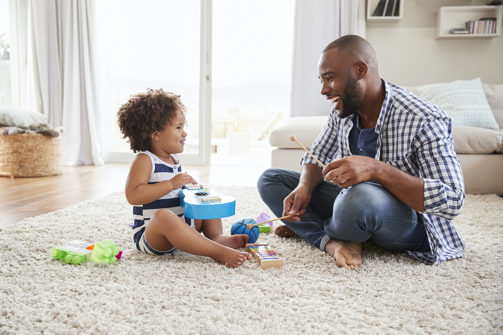 Dad and toddler daughter playing instruments in sitting room